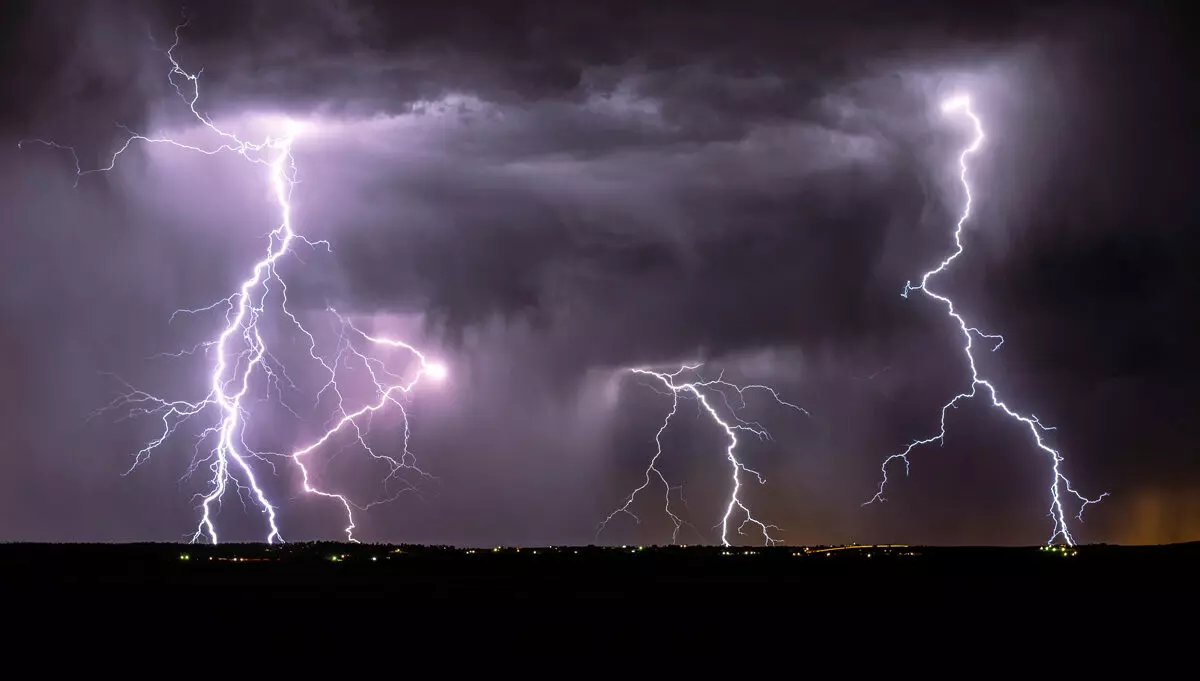 Lightning streak from a thunderstorm cloud at night in a rural setting. There are multiple lightning strikes coming from the thunderstorm.
